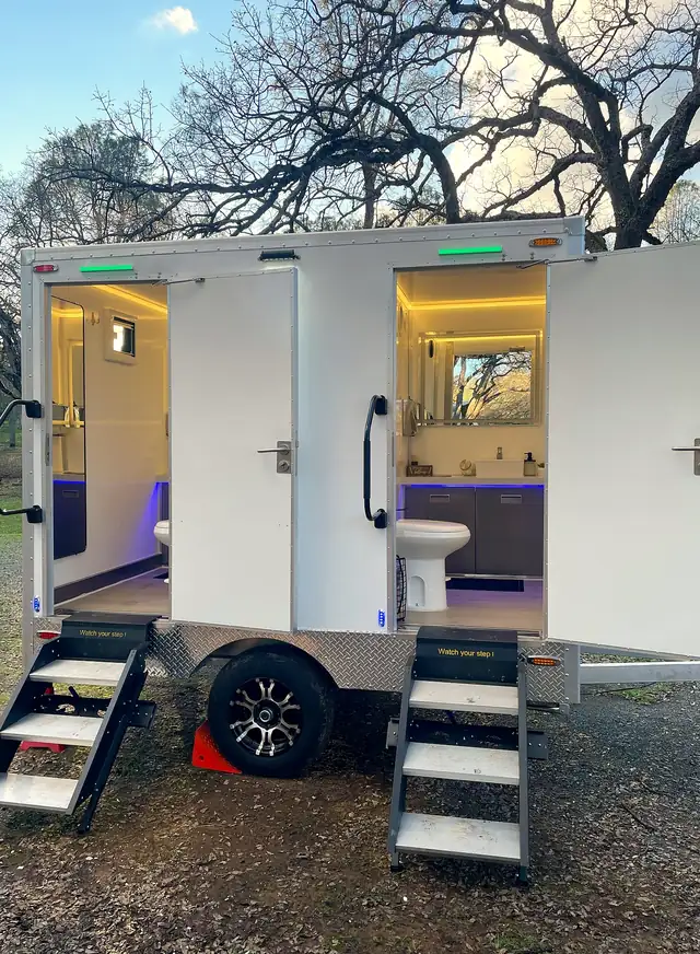 Luxury restroom trailer with both doors open and interior lights on
