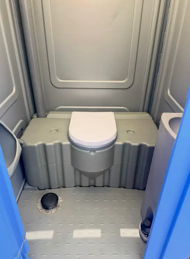 Freshly serviced porta potty interior with clean seat and floor