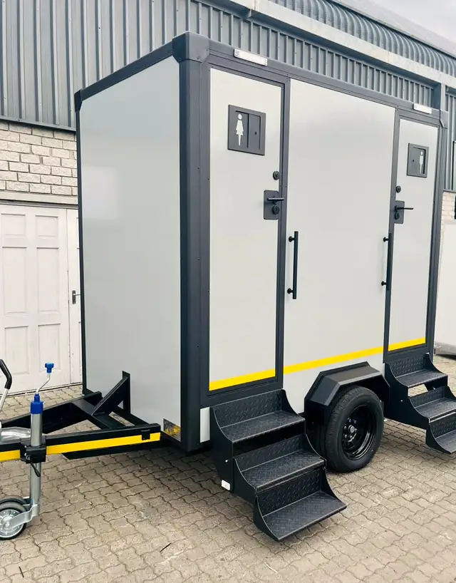 Two-stall restroom trailer with separate men's and women's doors and fold-down steps